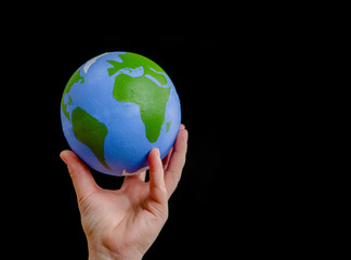 Close up woman holds planet in her hand. Ecology concept. Isolated on dark background. Empty space for text