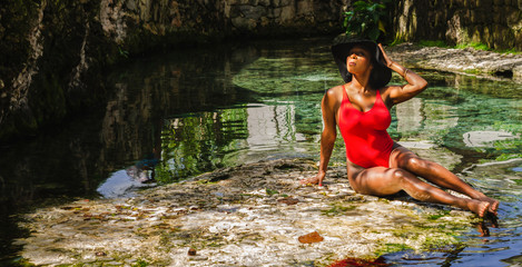 Black woman aged 25 to 30, enjoying the freshness of a natural source of water