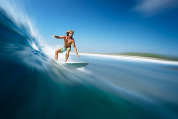 Fototapeta na wymiar Young man surfer with long hair surfs the fast and perfect ocean wave in Maldives