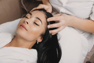 Fototapeta na wymiar Relaxed caucasian brunette waiting with closed eyes during a spa procedure for her skin and hair