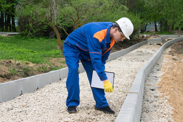 worker checks the height of the bardure of a new track in the park