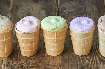 Colorful ice cream in waffle cups on a wooden background