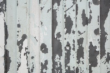 Old shabby metal sheet fence texture. Pattern of old metal sheet. Background of iron fence with peeled pieces of old cracked light paint layer.
