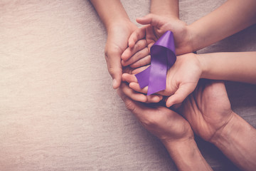 Adult and child hands holding purple ribbon, Alzheimer's disease, Pancreatic cancer, Epilepsy awareness, world cancer day