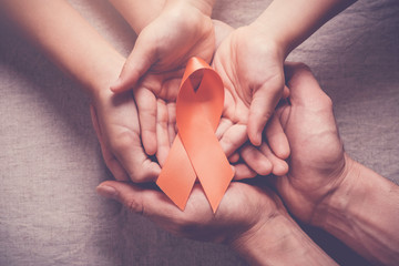 Adult and child hands holding orange Ribbons,  Leukemia cancer and Multiple sclerosis, COPD and ADHD awareness, world kidney day - obrazy, fototapety, plakaty