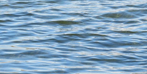 Light blue river water surface with sun glare