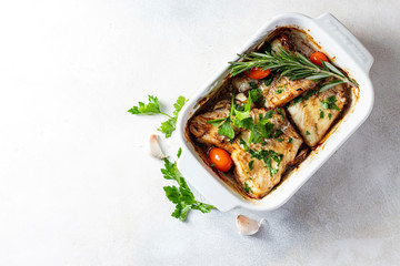 Baked filet of white fish in a white ceramic form on a baked background.