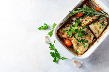Baked filet of white fish in a white ceramic form on a baked background.