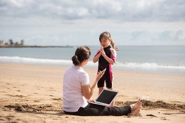 Daughter begs young mother to play with her at the beach