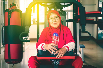 Senior muslim woman sitting on fitness machine