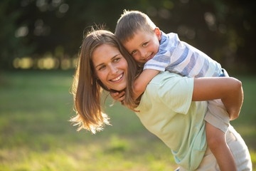 Smiling cute kid enjoying piggyback ride outdoors