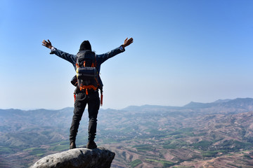 Male tourist on mountains cliff at the big rock to sightseeing range of mountain among green forest. Travel Lifestyle success concept adventure active vacations outdoor mountaineering sport landscape.