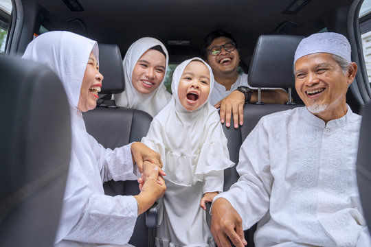 Three generation muslim family sitting in two rows of passenger seats in car
