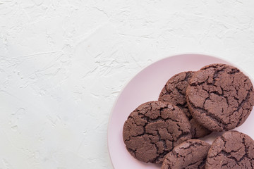 Top view of chocolate chip cookies on a pink plate on white concrete background. From above. copy space