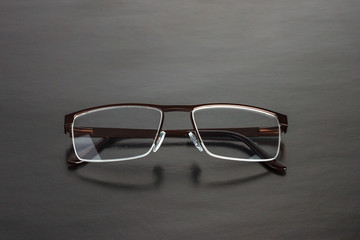 The male brown half-rim medical eyeglasses with folded temples on a black background