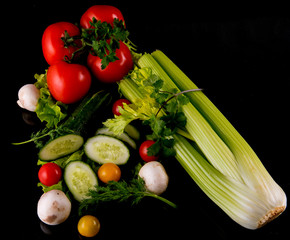Fresh vegetables, cucumber, mushrooms, onions, cherry tomatoes, lettuce on a black background, close-up, space for text