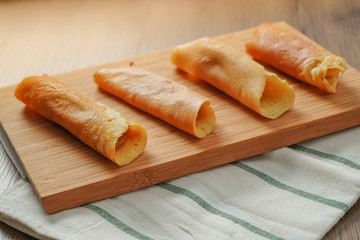 filled pancake roll assorted flavors on bamboo chopping board placed on white and green striped cloth on wooden table