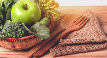 close up green apple with mixed green vegetable in  basket and wooden fork and spoon for healthy organic green food concept