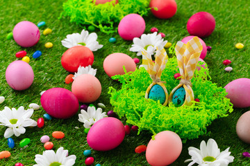 Close up photo of colored Easter eggs and candies on grass