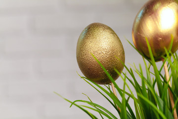 Golden colored Easter eggs stuck to artificial grass