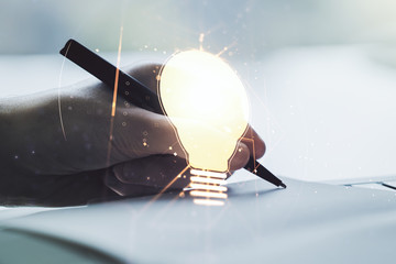 Double exposure of creative light bulb hologram with hand writing in diary on background, research...