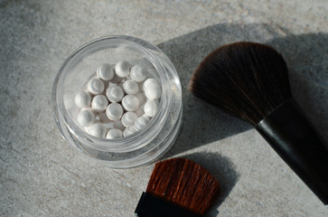 White pearl ball face powder, blush, makeup brushes on a light background, top view, close up....