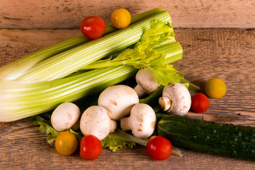 Fresh vegetables, celery, lettuce, cherry tomatoes, mushrooms, mushrooms, cucumber on a wooden Board, close-up, space for text