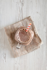 Homemade New England Chocolate Milkshake in a Glass Jar Mug on a white wooden background, top view. Overhead, from above, flat lay. Copy space.