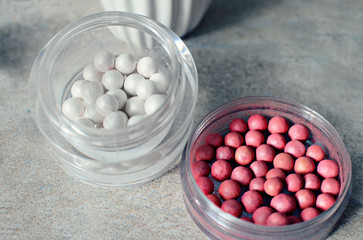 White pearl ball face powder for highlighting, blush on a gray background, top view, close up. 