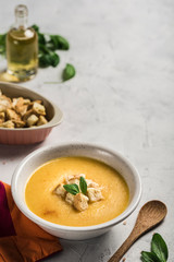 Pumpkin and carrot soup with cream and spinach with crackers on a white background.