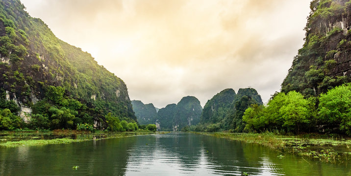 Tam Coc National Park - Tourists traveling in boats along the Ngo Dong River at Ninh Binh Province, Trang An landscape complex, Vietnam - Landscape formed by karst towers and rice fields