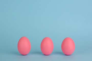  Three Easter pink eggs. Pink eggs in a row on a blue background. Copy space.