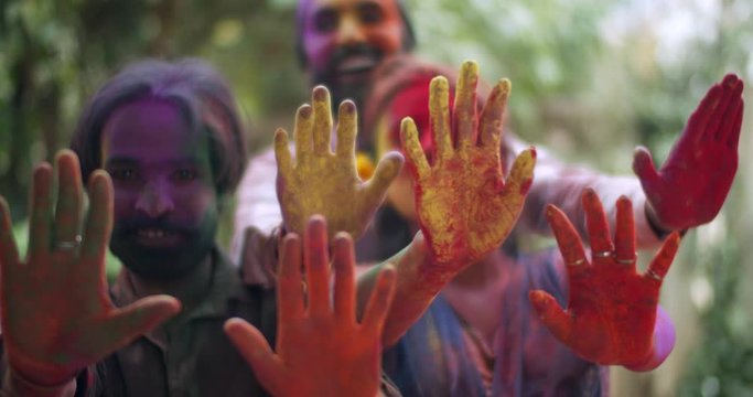 Closeup Handheld, Multi Colored Hands Of Happy Smiling Indian People Raised, Men And Women, In Front In Gulal For Celebrating Holi, Traditional Indian Festival Of Color. Bokeh Out-of-focus Foreground