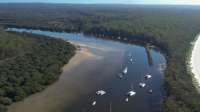 Aerial drone view of boats and yachts moored on Currambene Creek at Huskisson, Jervis Bay on the New South Wales South Coast, Australia, on a bright sunny day   