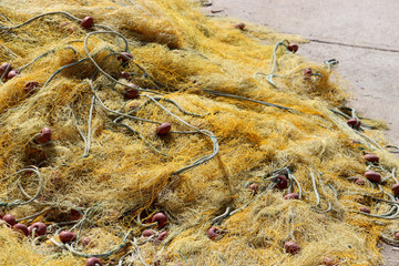 tangled yellow old fishing net any fisherman’s essential equipment for fishing lies on a concrete pier on a sunny summer day