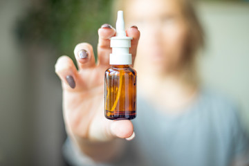 Nasal Spray, Female hand spraying nasal spray with blurred background. Medicine and health care concept. Antivirus treatment.