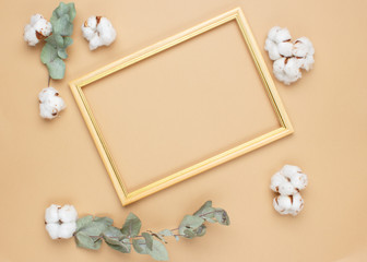 Eucalyptus leaves and cotton flowers on pastel beige background. Flat lay, top view. Copy space.