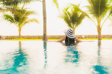 Obraz premium Portrait beautiful young asian woman relax around outdoor swimming pool in hotel resort with palm tree at sunset or sunrise