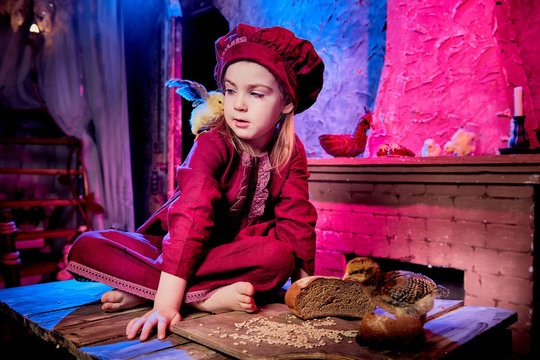 Small girl with little chicken in village interior in the room with wooden table. Easter, holiday and child concept