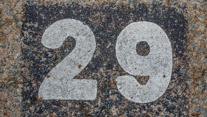 Faded and weathered number twenty nine painted on a rough street surface outdoors image in horizontal format with copy space