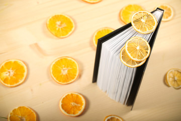 the book is sideways on the table, with dry slices of orange and lemon on it
