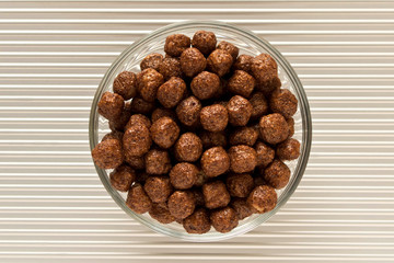 Chocolate cereal flakes in a plate on a silver background. The view from the top.