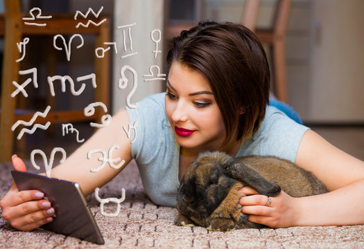 The girl lies on the carpet and reads her horoscope