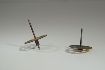 Gear wheeels from an old clock spins on a white surface, the gyroscope effect lets them balance like teetotums.