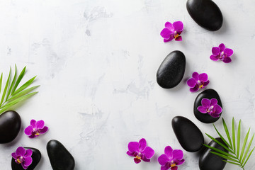 Obraz na płótnie Canvas Spa composition with flowers, green leaves and massage stone on white background top view. Beauty treatment and relaxation concept. Flat lay. .