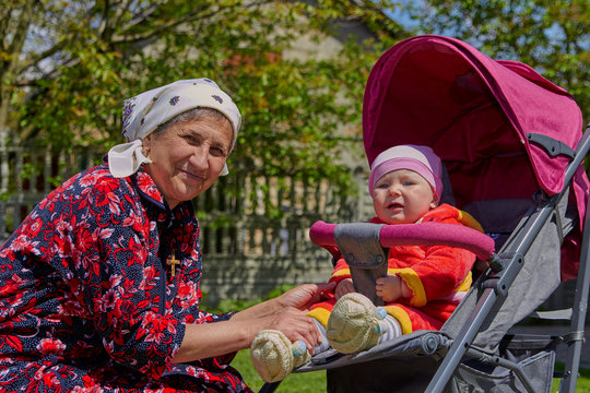 senior woman and baby in a stroller,happy grandmother sat down with her granddaughter in a trolley for a walk
