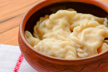 Traditional Ukrainian meat dumplings. Russian boiled pelmeni served in a bowl with sauce on white tablecloth