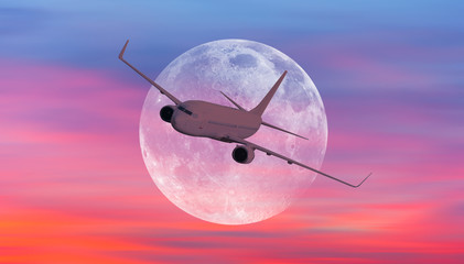 Passenger airplane in the sky against super moon at sunset "Elements of this image furnished by NASA "