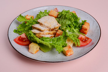 Healthy green organic caesar salad with cheese and croutons and grilled chicken served in white plate.