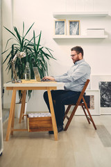 Young male architect sitting at his desk and typing.	